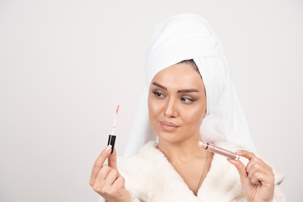 Young woman in a bathrobe looking at a lipstick .