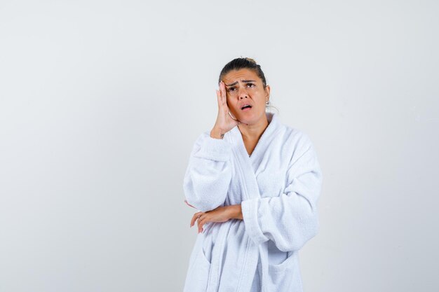 Young woman in bathrobe looking up and looking amazed