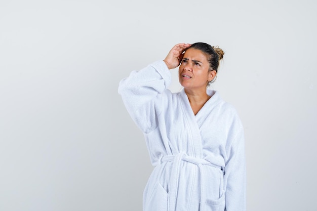 Young woman in bathrobe looking up and looking thoughtful