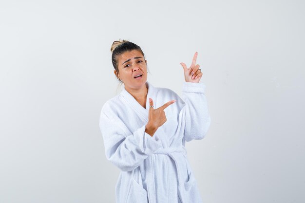 Young woman in bathrobe pointing aside and looking confident