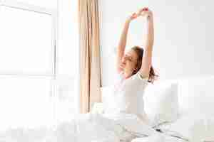 Free photo young woman in bed indoors stretching