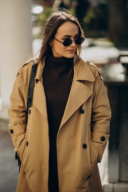 Foto gratuita giovane donna in cappotto beige in posa per strada