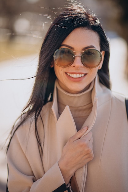 Free photo young woman in beige coat walking in the street