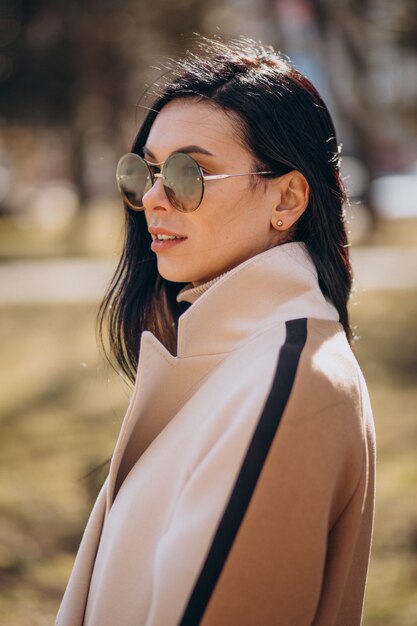 Young woman in beige coat walking in the street