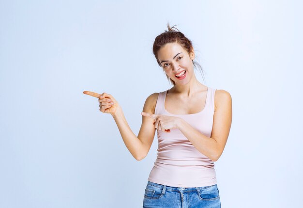 Young woman in beige shirt pointing at something on the left