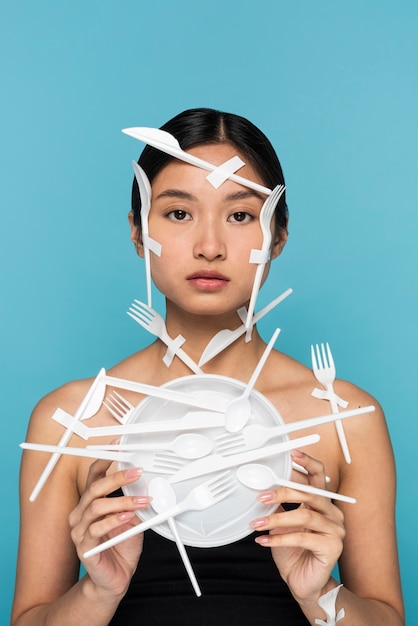 Young woman being covered in white plastic tableware