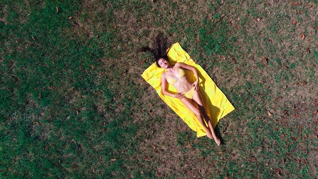 young woman in bikini lying on a meadow