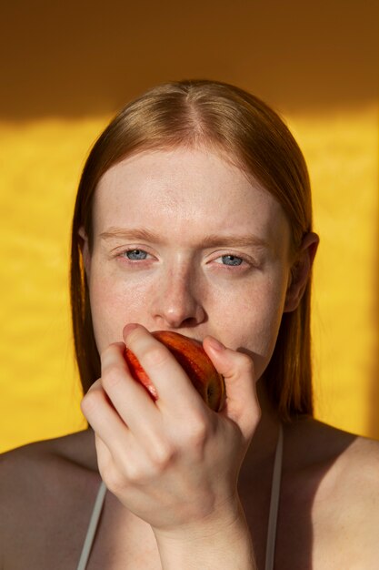 リンゴを噛む若い女性正面図