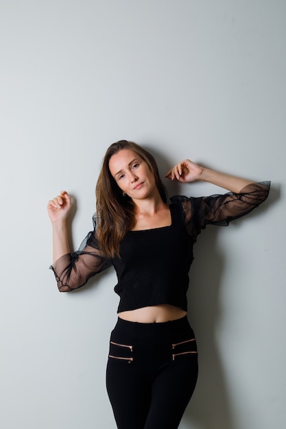 Young woman in black blouse and black pants posing at the front and looking charming