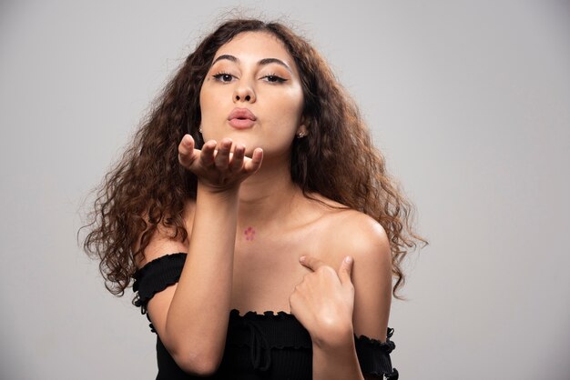 Young woman in black blouse blowing an air kiss. High quality photo