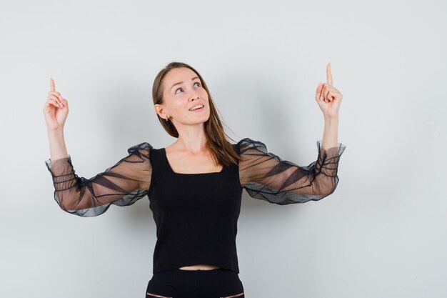 Young woman in black blouse looking away while pointing up and looking patient 