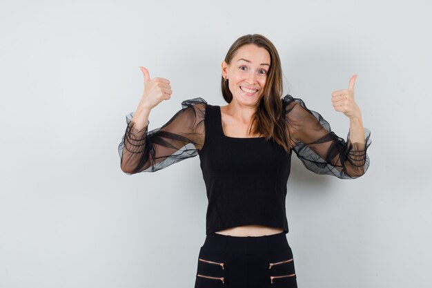 Young woman in black blouse showing thumb up and looking merry 