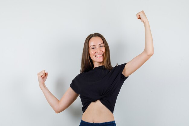 Young woman in black blouse stretching her arms and looking powerful