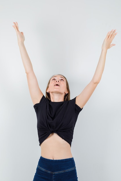 Young woman in black blouse stretching her arms while looking up and looking blissful