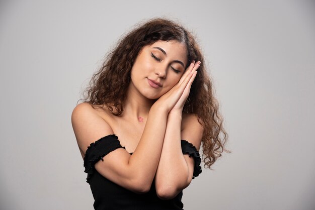 Young woman in black blouse with curly hair posing. High quality photo