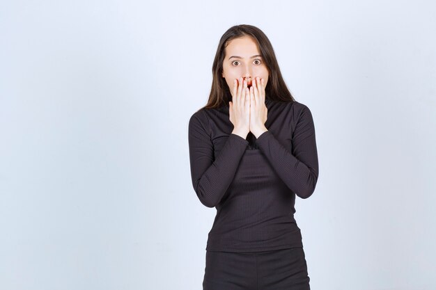 Young woman in black clothes looks terrified and scared