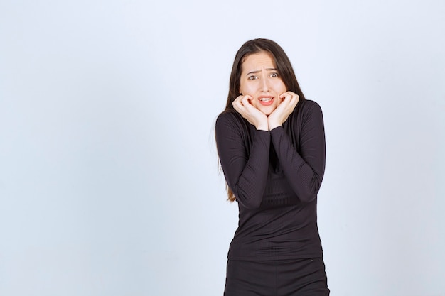 Young woman in black clothes looks terrified and scared