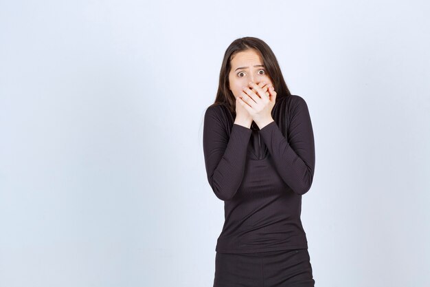 Young woman in black clothes looks terrified and scared