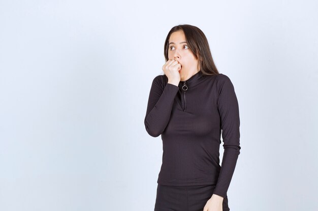 Young woman in black clothes looks terrified and scared