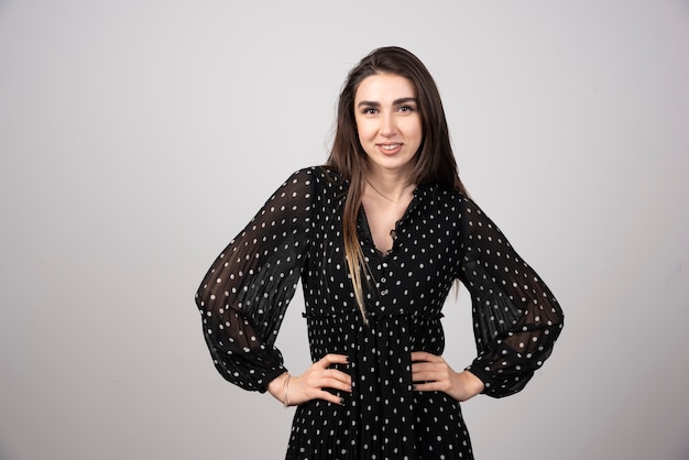 Free photo young woman in black dress posing on gray.