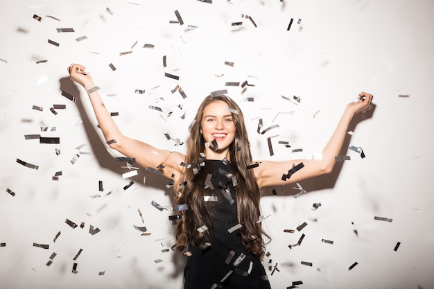 Free photo young woman in black dress sitting on the floor aroung confetti isolated on white background