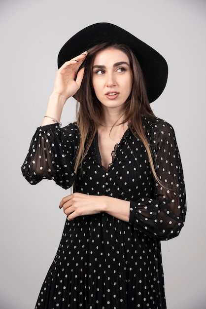 Giovane donna in cappello nero che sembra seria.