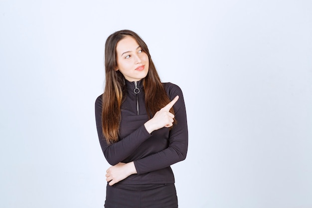 Free photo young woman in black pointing to the right side