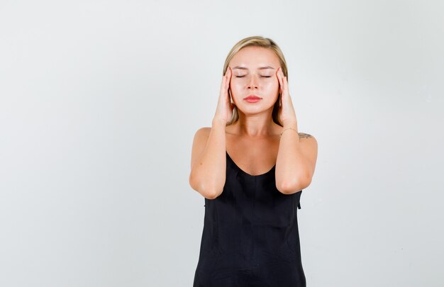 Young woman in black singlet holding head with hands and looking tired