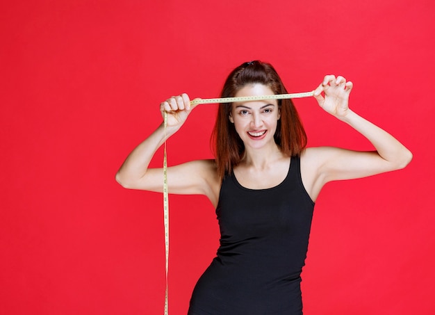 Free photo young woman in black singlet holding a measuring tape