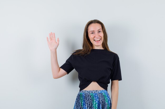 Young woman in black t-shirt and blue skirt showing stop gesture and looking attractive