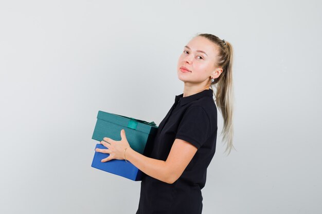 Young woman in black t-shirt carrying gifts and looking pretty