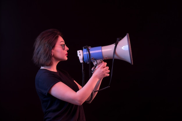 Free photo young woman in black t-shirt holding megaphone