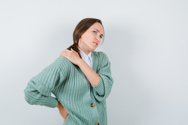 Free photo young woman in blouse, cardigan suffering from backache and looking fatigued , front view.