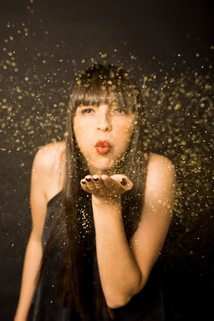 Young woman blowing confetti from hand 