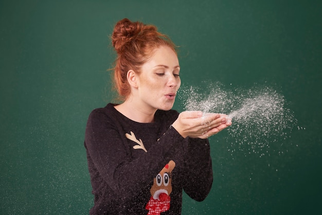 Free photo young woman blowing fake snow