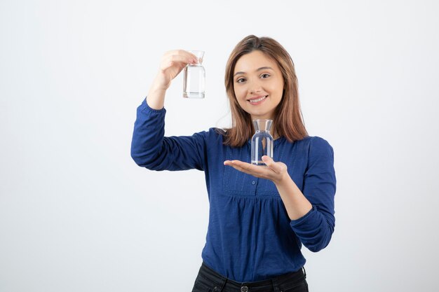 Young woman in blue blouse holding water in her hands. 