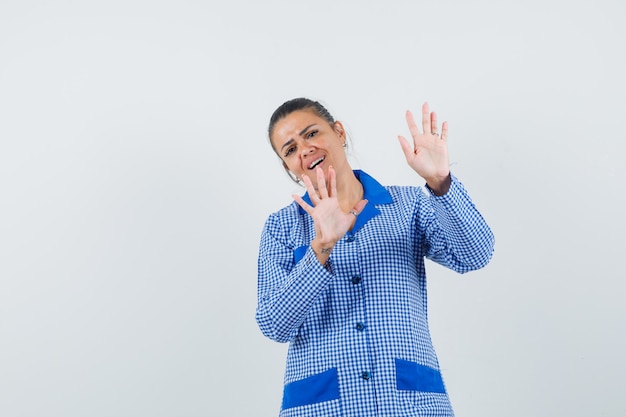 Young Woman In Blue Gingham Pajama Shirt Showing Restriction Gesture And Looking Pretty , Front View.