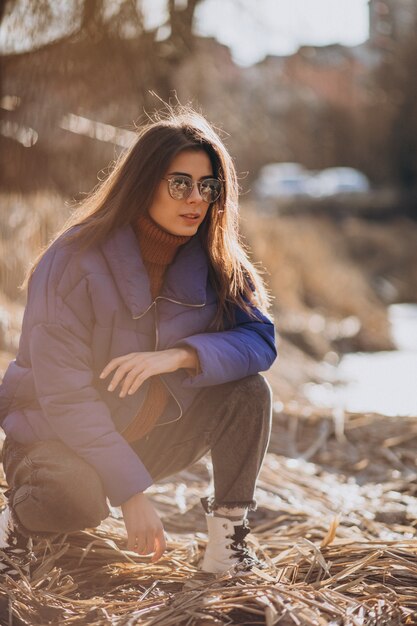 Young woman in blue jacket outside in park