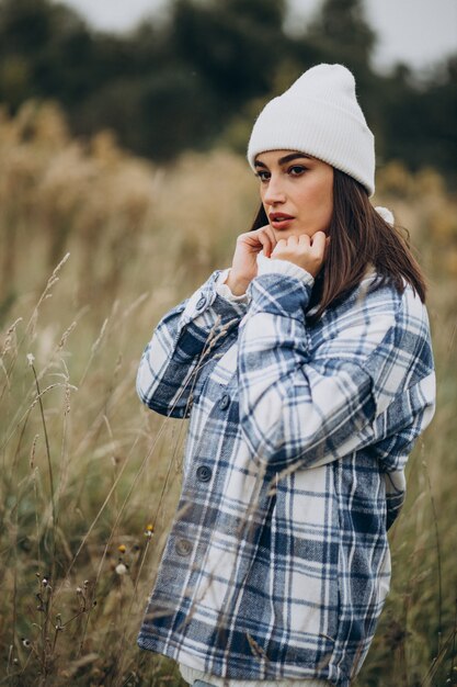 Young woman in blue jacket and white hat walking in autumnal forest