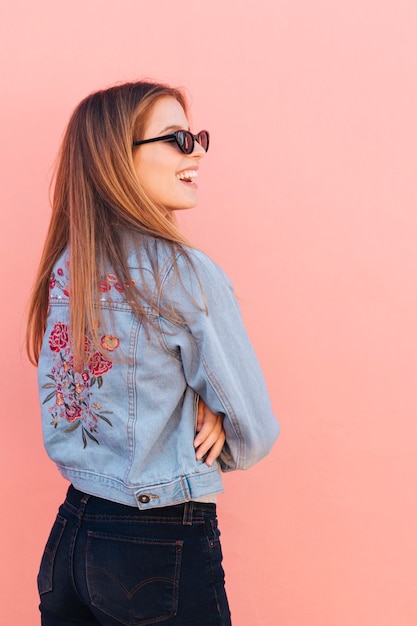 Foto gratuita la giovane donna in giacca blu con le sue armi ha attraversato la condizione contro il contesto rosa