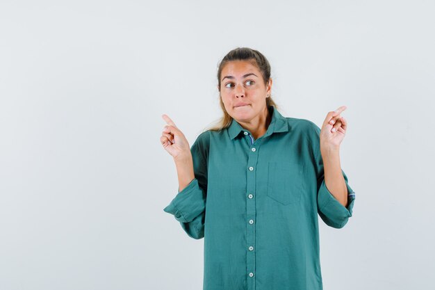 young woman in blue shirt pointing at reverse sides and looking puzzled