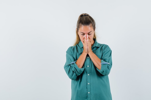 Giovane donna in camicia blu che prega per qualcosa e che sembra promettente