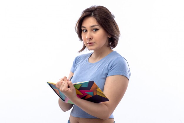 Young woman in blue shirt writing down notes