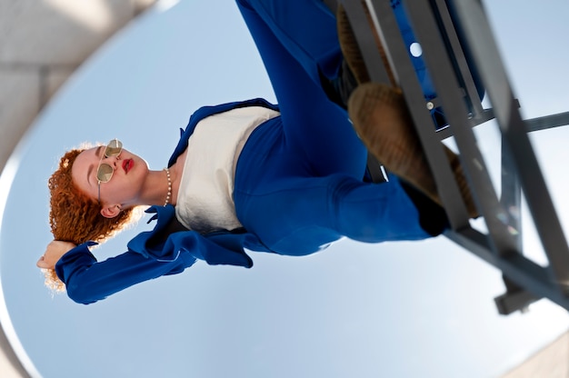 Young woman in blue suit posing with mirror outdoors