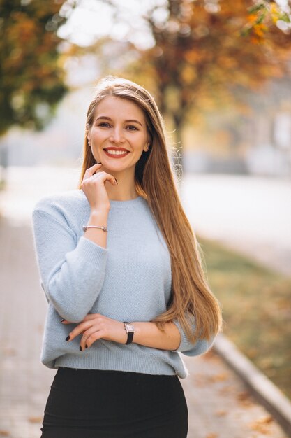 秋の公園で青いセーターの若い女性