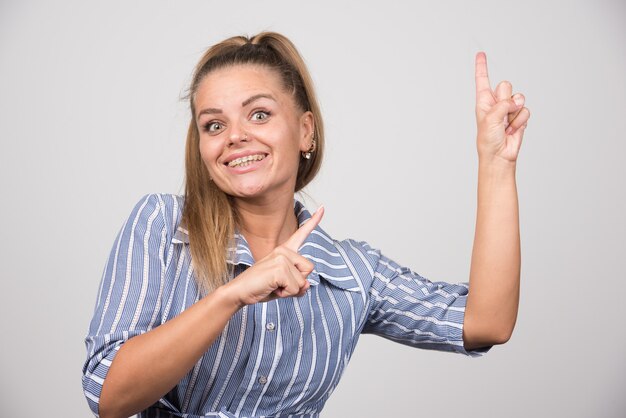 Young woman in blue sweater pointing at something.