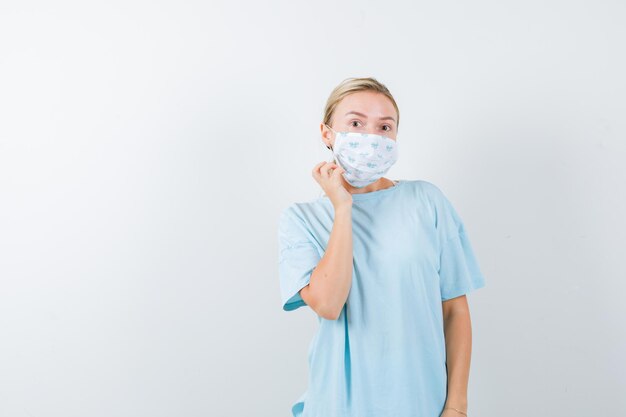 Young woman in a blue t-shirt with a medical mask