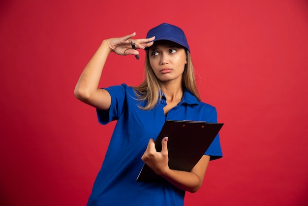 Young woman in blue uniform holding clipboard with pencil .