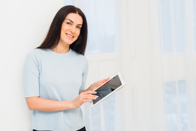 Foto gratuita giovane donna in blu facendo uso della compressa