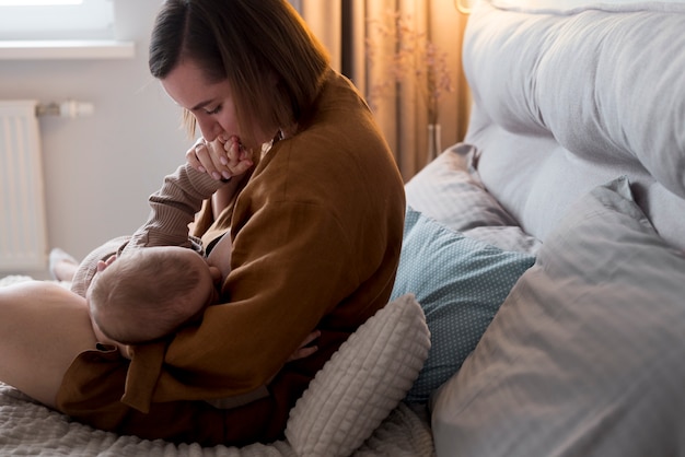 Free photo young woman breastfeeding her cute baby